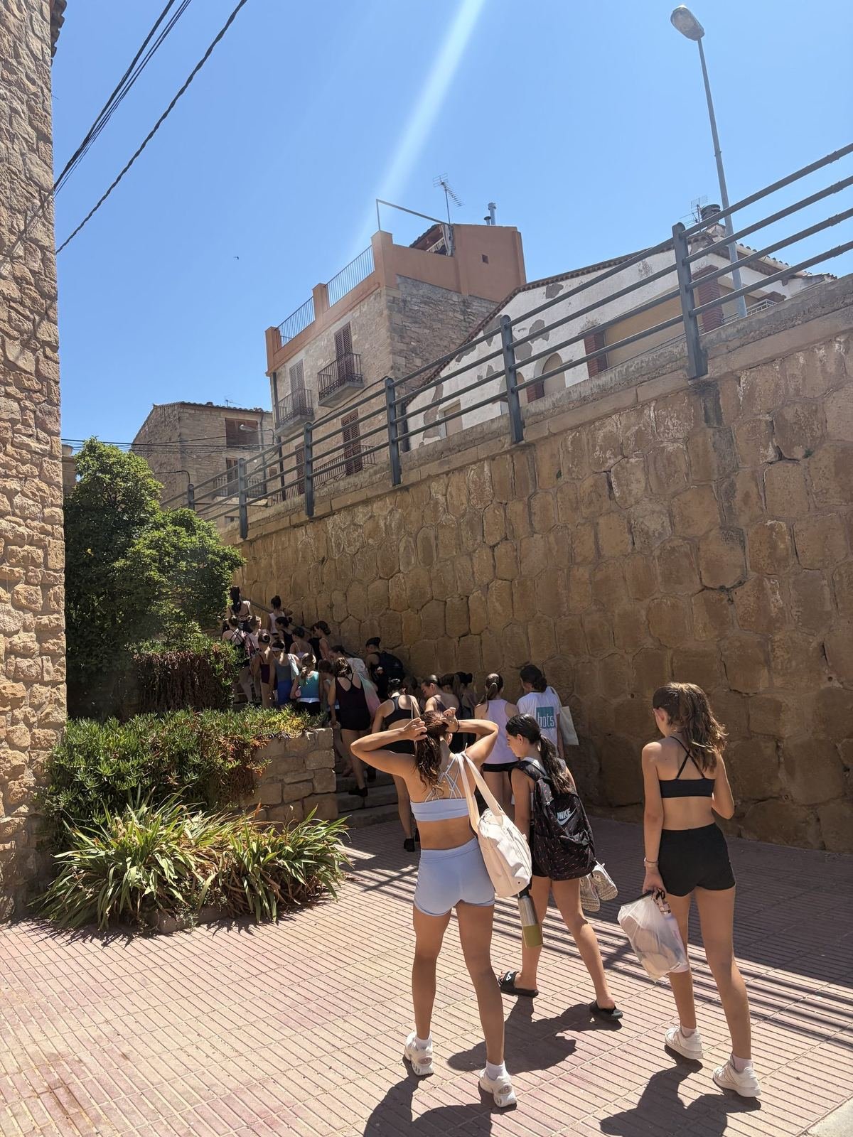 Un grup d'alumnes passeja pels carrers del poble sota un cel blau